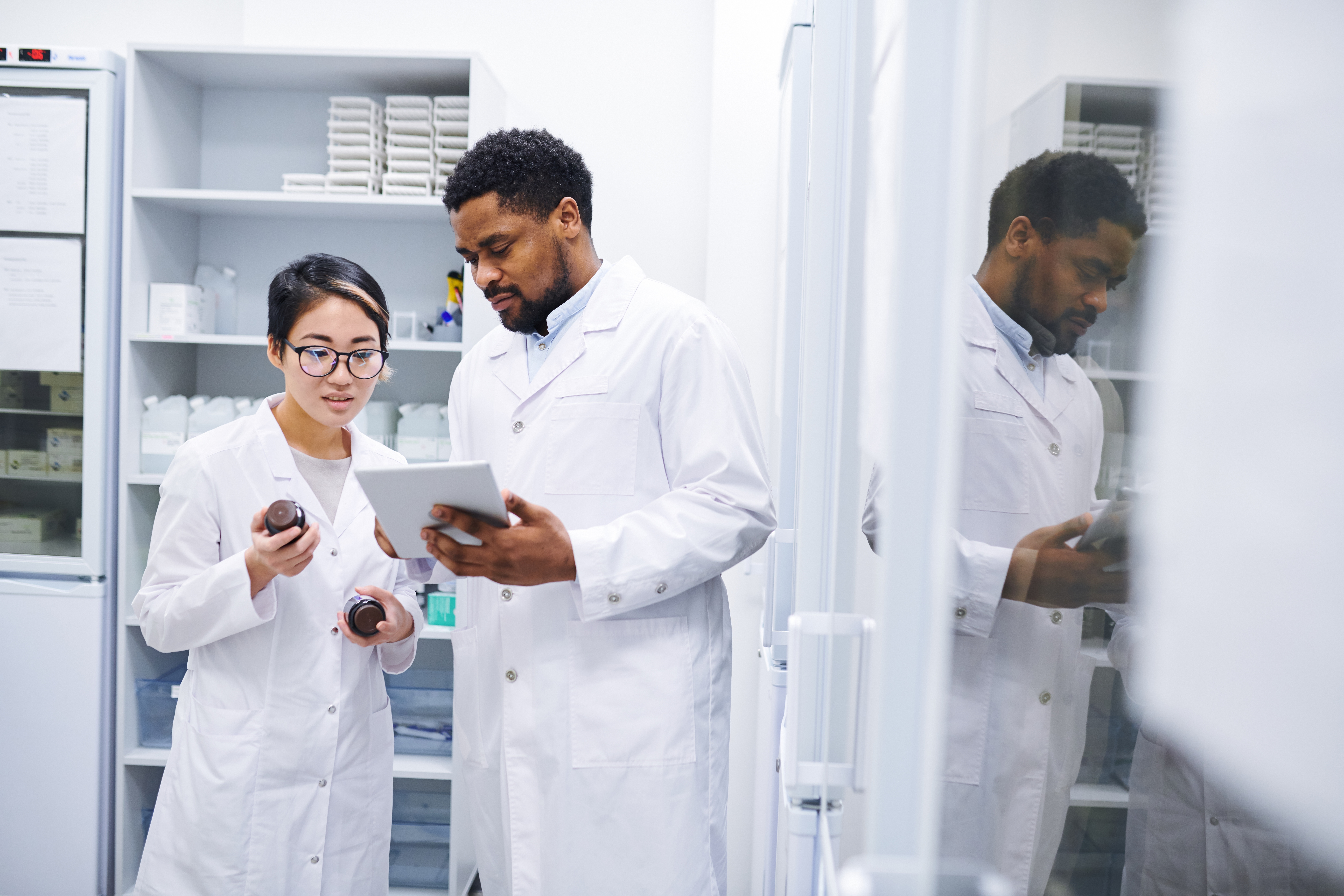 Healthcare professionals review patient charts on a tablet while standing beside a doctor in a clinical office, collaborating on accurate medical documentation and data entry.